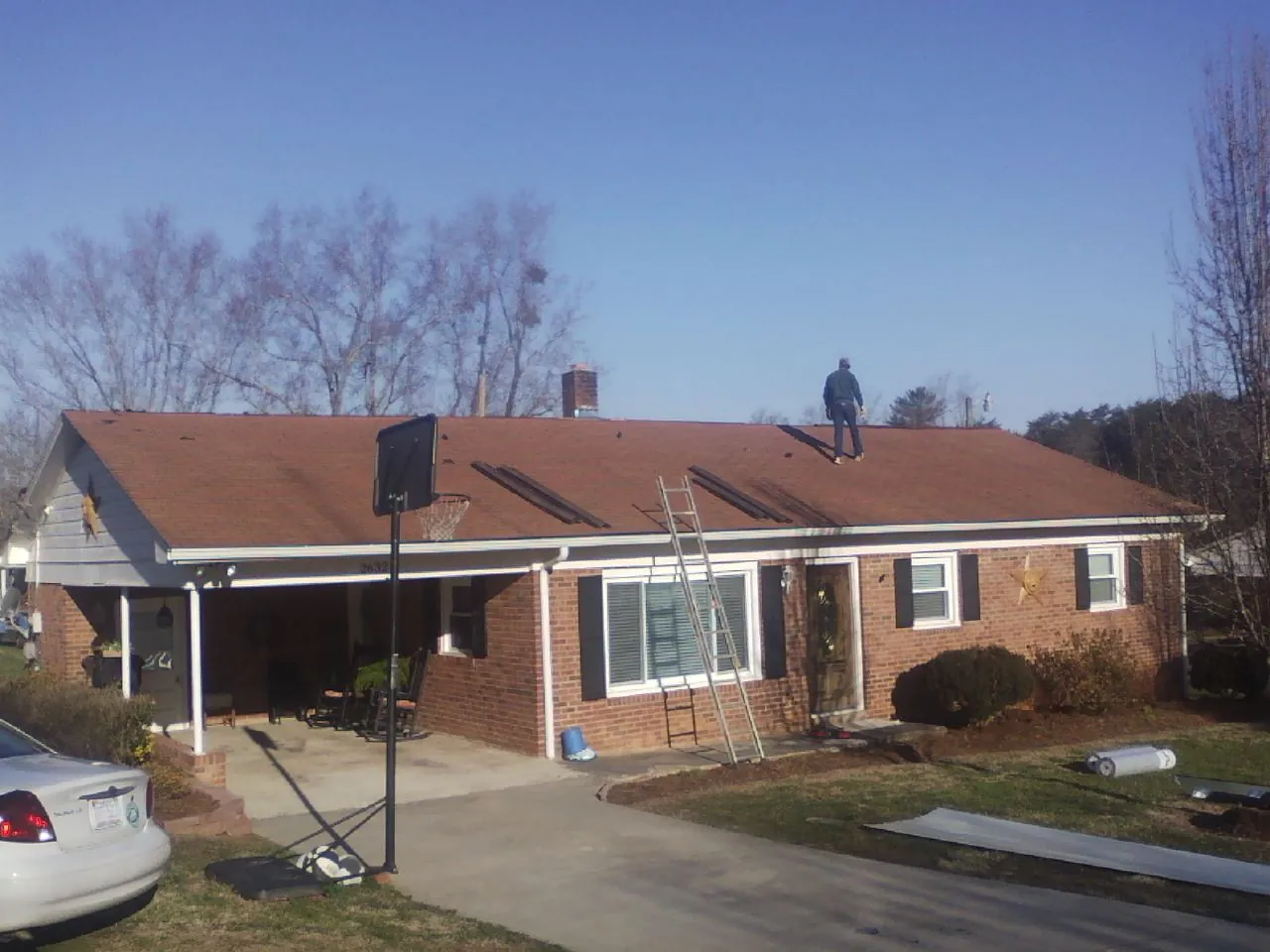 Roofer stripping a shingle roof on a brick ranch before metal panels in Beaver Creek