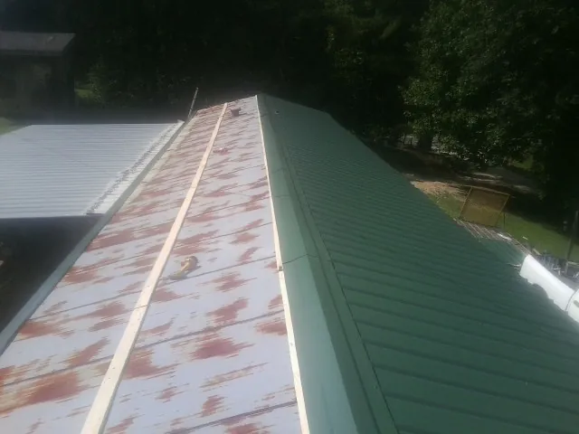 Old rusted panels beside newly installed green metal roofing — Wind Damage Roof Repair by Roofing Brothers in Beaver Creek