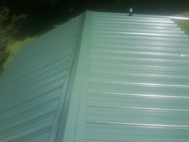 New green metal panels meeting at the ridge of a roof — Flat Roof Repair work by our crew in Beaver Creek