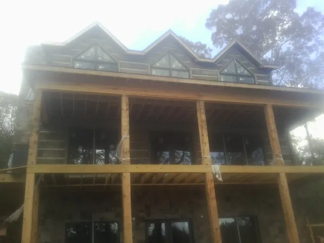 Dormers and porch framing on a large log home under construction — Roof Coating work by our crew in Beaver Creek