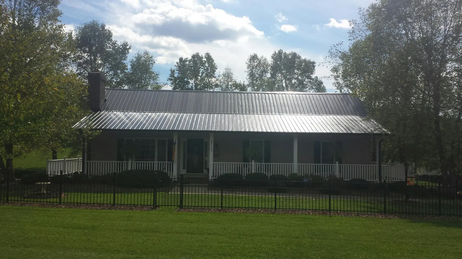 Gray metal roof on a brick ranch with a full width front porch — Gutter Guard Installation work by our crew in Beaver Creek