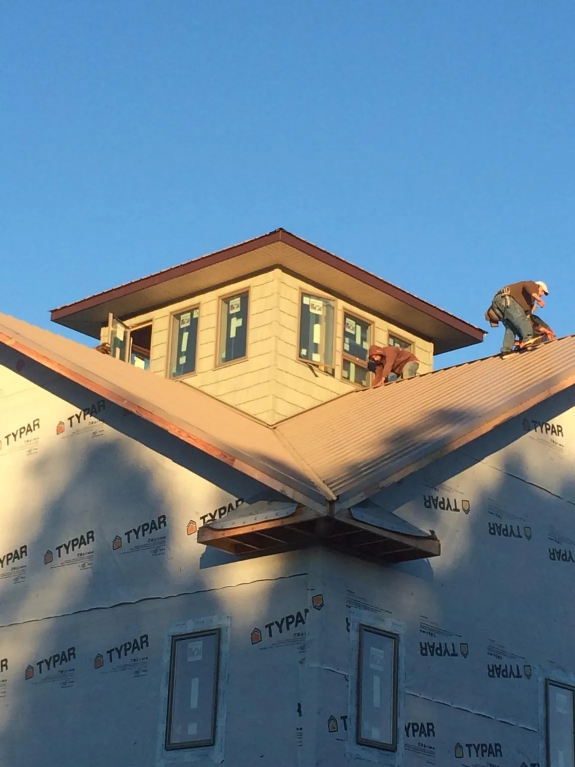 Roofers working around a rooftop cupola on a new metal roof at sunset — Roof Waterproofing in Beaver Creek by Roofing Brothers